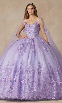 A woman wears the Juliet 1442 Quinceañera Dress, featuring a lilac hue, floral embroidery, a fitted bodice, and sheer cape sleeves, standing against a neutral background.