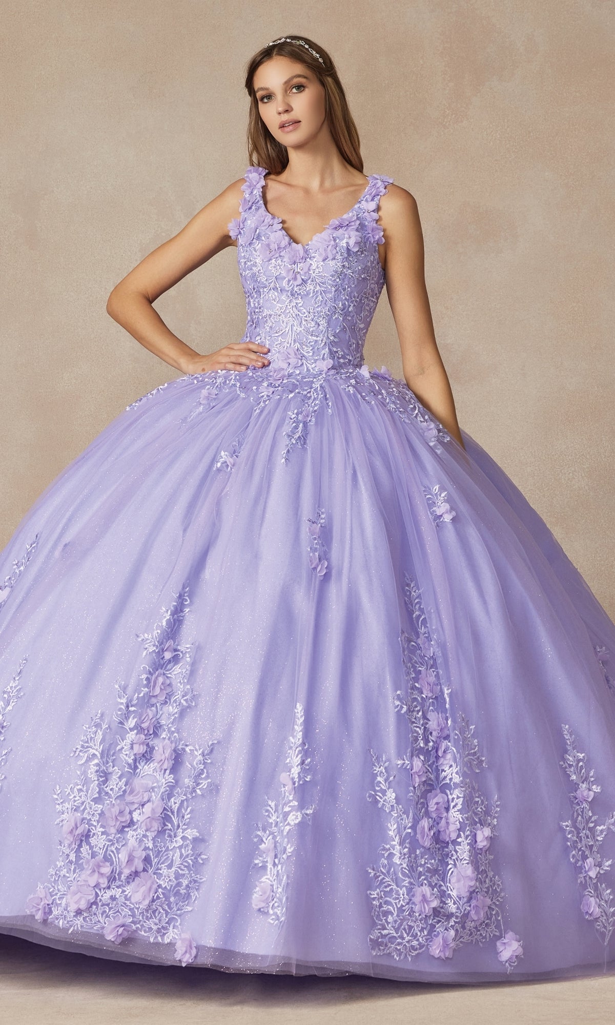 A woman stands against a neutral background wearing the Juliet 1437 Lilac Purple Quinceañera Dress adorned with floral appliqué details.