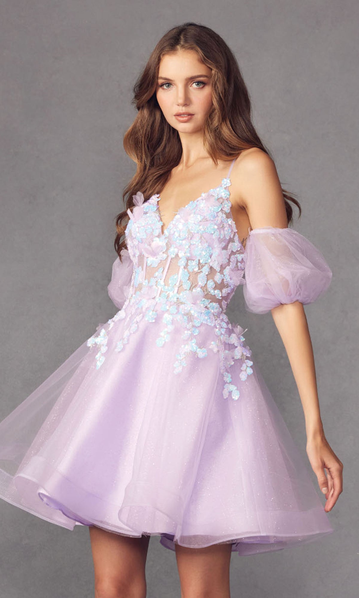 A woman wears the Puff-Sleeve Short Butterfly Homecoming Dress 901 in light purple, featuring sheer puff sleeves, butterfly appliqués, and a fitted bodice—ideal for a playful party look.
