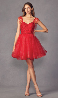 A woman wears the Short Babydoll Homecoming Dress with Feathers 881, featuring glitter fabric, feathered shoulder straps, and a flared skirt, as she stands against a plain gray background.