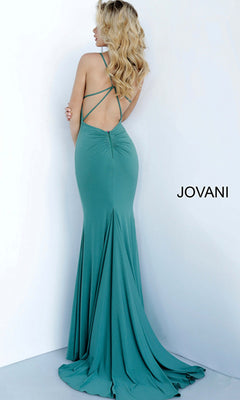 A woman with long blonde hair models the Jovani Strappy-Back Long Jersey Prom Dress 00512, featuring crisscross straps and a fitted teal floor-length design, standing against a white wall with "JOVANI" beside her.