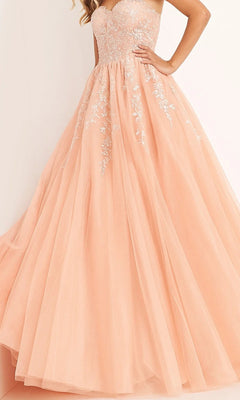 A woman wearing the Jovani 00915 long prom dress in light pink, showcasing a strapless, fitted lace-embroidered bodice and a flowing tulle ballgown skirt embellished with delicate white floral embroidery.