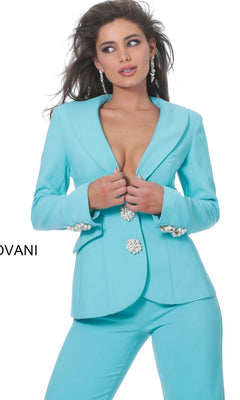 A woman wearing the Jovani 02637 Long Jumpsuit—a fitted light blue jumpsuit with jeweled buttons and earrings—stands against a white background.