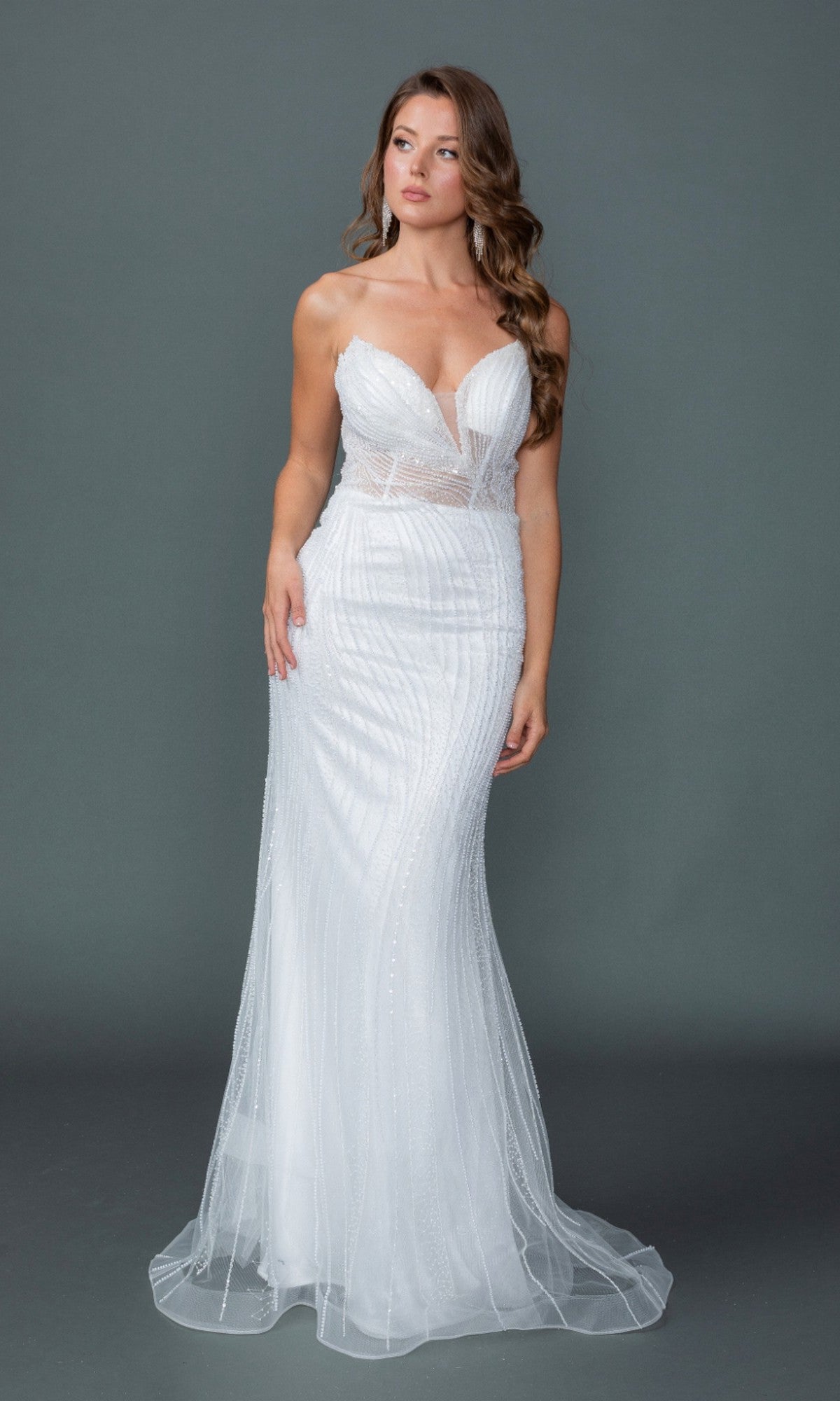 A woman wearing the Dancing Queen 0328 long wedding dress, featuring a strapless corset bodice, fitted white silhouette with sheer panels and a flared hem, stands against a plain gray background.