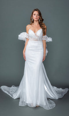 A woman wearing the Long Wedding Dress: Dancing Queen 0328 in off white, featuring an off-shoulder mermaid silhouette with a strapless corset bodice, sheer details, and a flowing train, stands against a plain gray background.