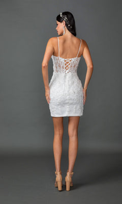 A woman stands facing away in the Long Wedding Dress 0329 by Dancing Queen, a white gown adorned with floral lace appliqués, featuring thin straps, a lace-up back, and a delicate appliquéd skirt. She completes the look with nude high heels and a pearl hair accessory, set against a plain gray background.