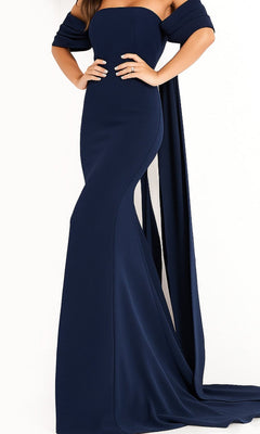 A woman poses with her hands on her hips against a plain white background, wearing the Jovani 04350 Long Prom Dress—a fitted, strapless floor-length gown in navy crepe with elegant off-the-shoulder drapes.