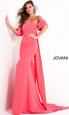A woman models the Long Prom Dress by Jovani 04350—a strapless, floor-length bright pink gown with a matching draped shawl—standing near a white wall featuring the "JOVANI" logo.