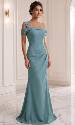 A woman wears the Long Formal Dress: Jovani 06723 in a fitted, seafoam off-the-shoulder design, featuring a graceful sheath silhouette as she stands in a marble-floored, white-walled interior with elegant wall molding—perfectly embodying the sophisticated charm of this Jovani formal gown.