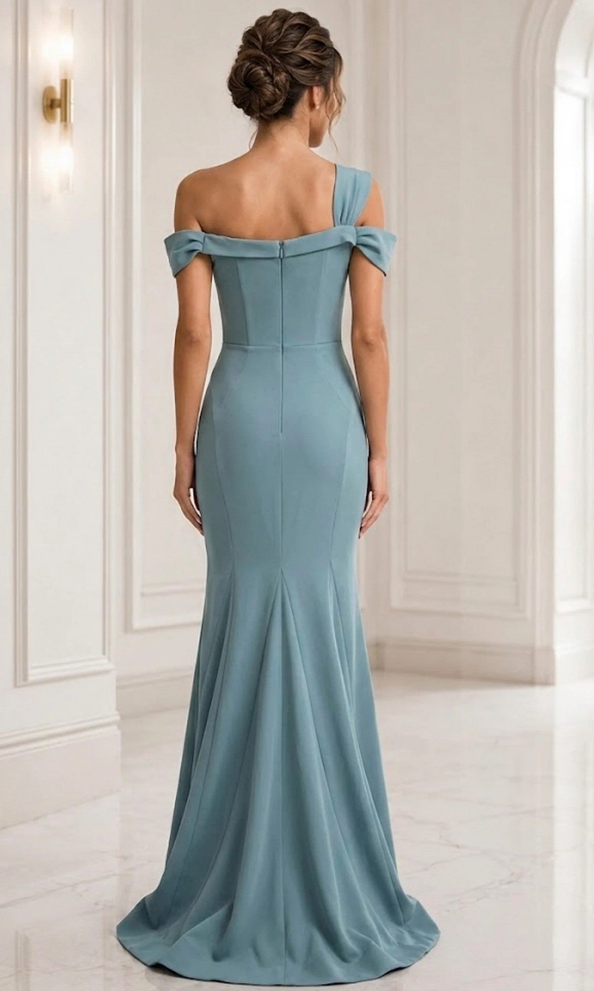 A woman stands with her back to the camera in a white, modern interior, wearing the elegant, floor-length Jovani 06723 Long Formal Dress in light blue with off-the-shoulder detailing.