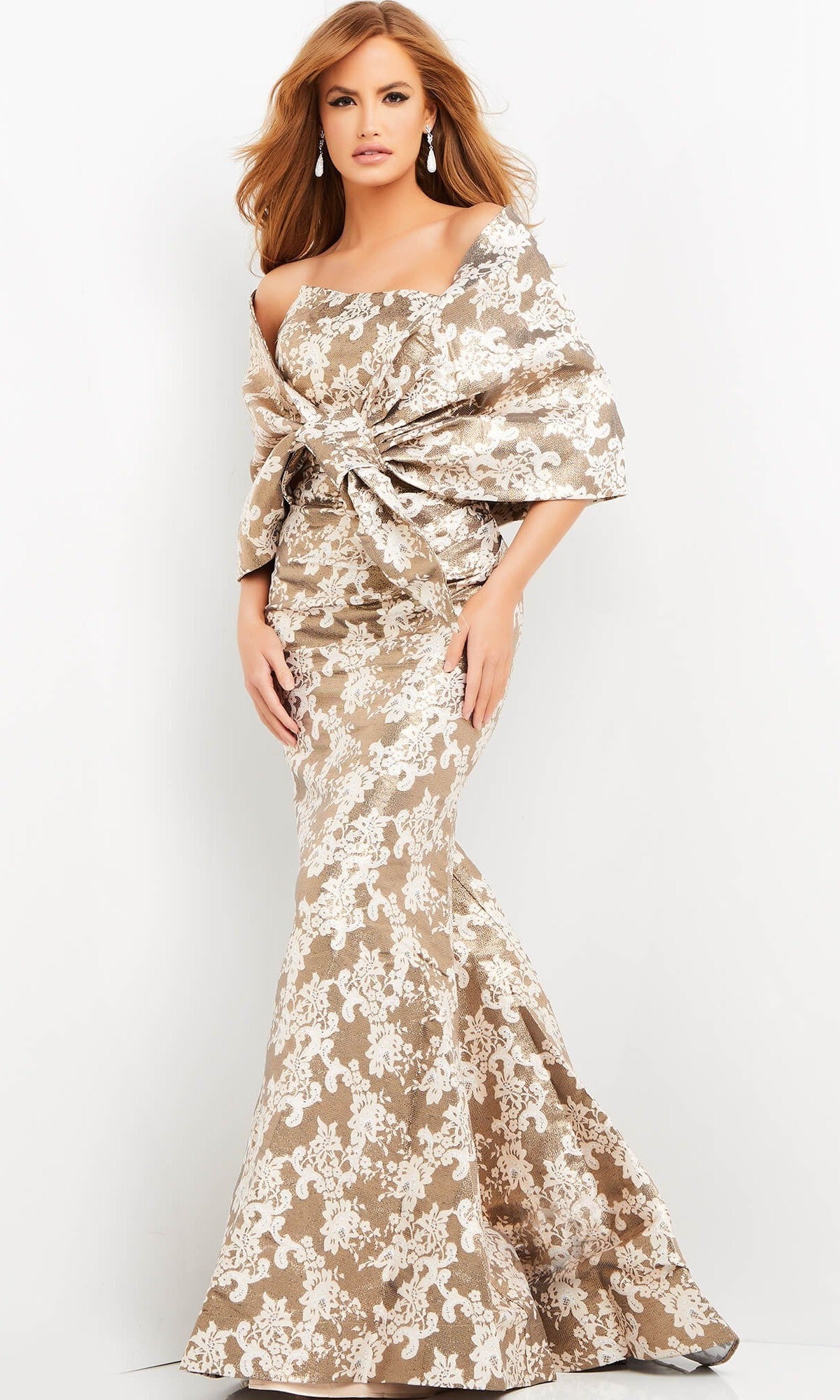 A woman in the Jovani 06760 long formal dress, featuring a champagne jacquard floral pattern and an off-the-shoulder design, poses gracefully against a plain white background.