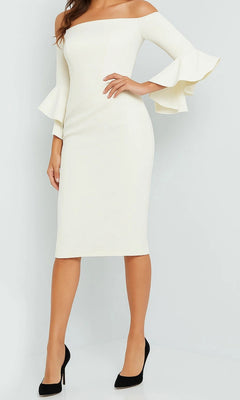 A woman stands against a plain background wearing the Jovani 07066 short wedding guest dress—a knee-length, off-the-shoulder white sheath with flared sleeves—paired with black high heels.