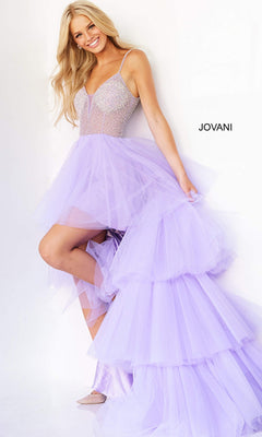 A woman models the Jovani High-Low Sheer-Bodice Prom Dress 07231, a sleeveless lavender gown with an embellished bodice, standing against a white backdrop featuring "JOVANI" on the wall.