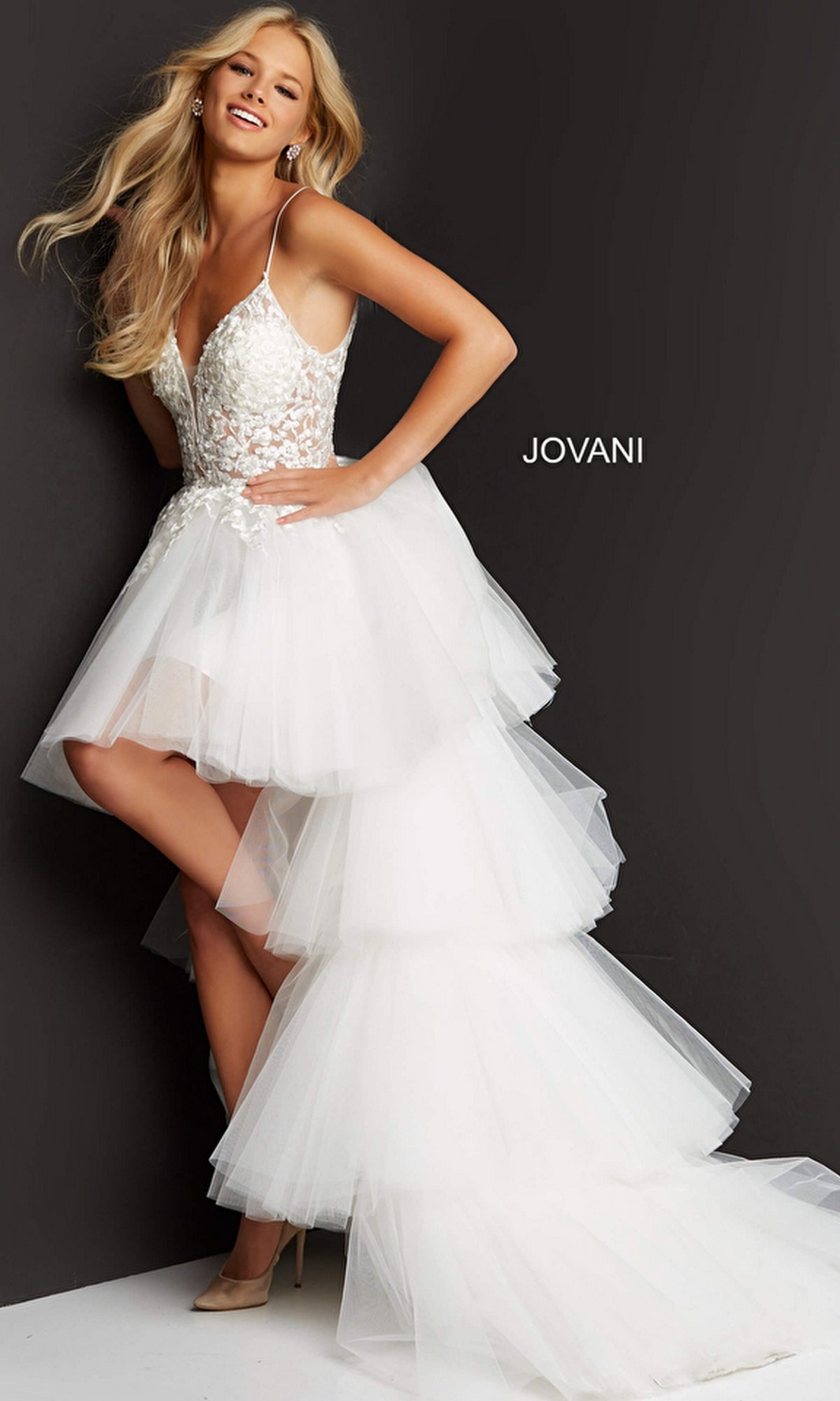 A woman poses in the Jovani Ruffled High-Low Prom Dress 07263, which features an embroidered bodice, thin straps, and a layered tulle skirt, set against a black background with “JOVANI.”.