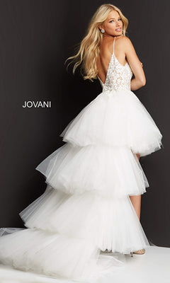 A woman stands against a dark background wearing the Jovani Ruffled High-Low Prom Dress 07263, featuring a white tiered tulle train and an embroidered bodice.