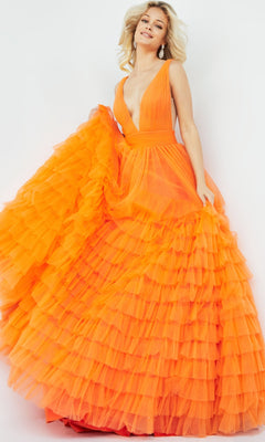A woman smiles and poses in the Jovani V-Neck Long Ruffled Prom Ball Gown 07264, featuring bright orange fabric, dramatic ruffles, and a deep V-neckline against a plain background.