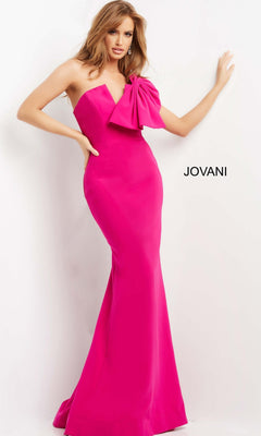 A woman wears the Jovani 07306 long formal dress—bright pink, strapless, with a mermaid silhouette and a statement bow on the bodice—posing against a white background with “Jovani” displayed at her side.