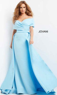 A woman wearing the Jovani 07443 Long Formal Dress—a light blue, off-the-shoulder, floor-length gown with a full skirt—stands beside a wall with “JOVANI” displayed on it.