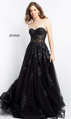 A woman poses against a plain background in the Jovani Strapless Long Lace A-Line Prom Dress 07901, featuring floral appliqué details and a sheer bodice. The word "JOVANI" appears on the left, highlighting this gorgeous gown.