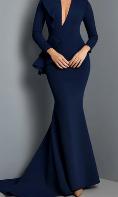 A woman wears the Long Formal Dress: Jovani 07934 in navy, a fitted gown featuring long sleeves, a deep V-neckline, and elegant ruffle detailing, as she stands against a plain gray background. This sophisticated designer dress is the ideal choice for any mother-of-the-bride seeking timeless elegance.
