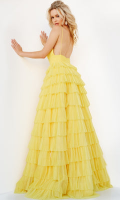 A woman poses with her back to the camera in the Jovani Open-Back Long Tiered Prom Ball Gown 08480, a yellow spaghetti-strap dress, against a white background.