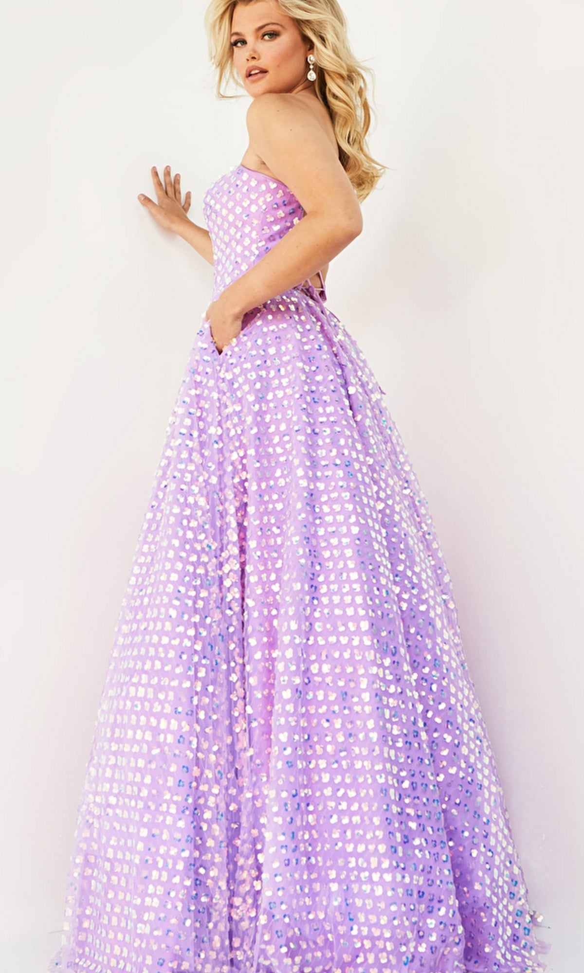 A woman poses in the Jovani Plus-Size Strapless Long Prom Dress 08605B, a floor-length lavender gown decorated with shiny silver heart-shaped sequins.