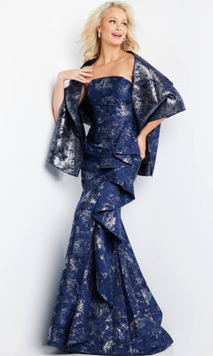 A woman stands against a plain light background, dressed in the Jovani 08685 long formal gown in navy—a strapless evening dress featuring shimmering metallic brocade patterns and complemented by a matching shawl, for an elegant and timelessly sophisticated look.