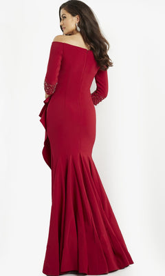 A woman stands facing away against a plain white background, wearing the Long Formal Dress: Jovani 08699—a long, fitted, off-shoulder red gown with embellished sleeves.