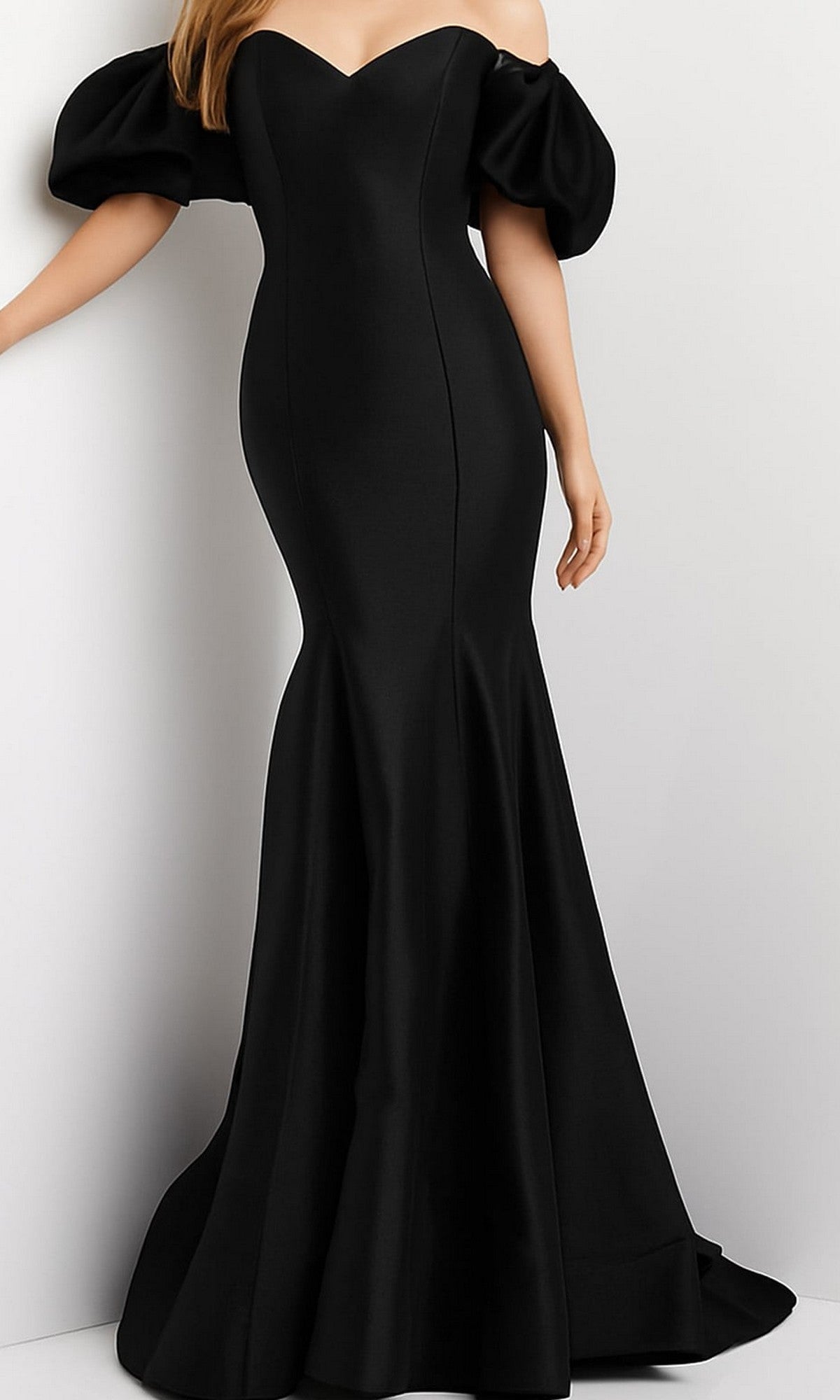 A woman wearing the Jovani Puff-Sleeve Long Mermaid Prom Dress 09031 in black, featuring a fitted off-the-shoulder design with puff sleeves, stands against a plain light-colored wall.