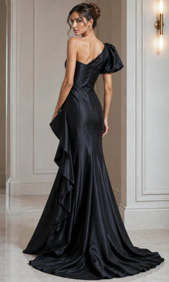 A woman stands in an elegant interior wearing the Jovani 09201 long formal dress—a fitted, black, one-shoulder gown featuring a ruffled side detail.