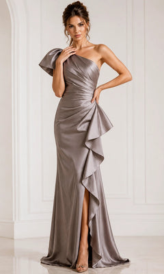 A woman stands in a light-colored, minimally decorated room, wearing the Jovani 09201 long formal dress in taupe—a one-shoulder gown featuring ruffled detailing, a shiny finish, and a front slit.