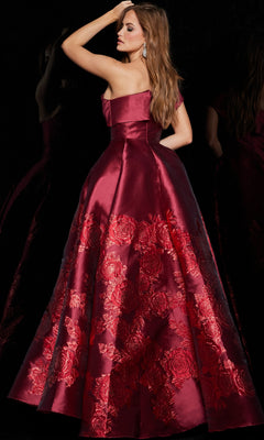 A woman poses against a black background, looking over her shoulder in the Jovani Long Red One-Shoulder Prom Ball Gown 09610 with floral embroidery.