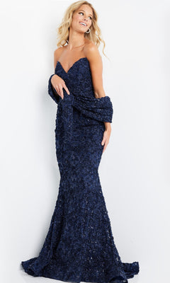 A woman wearing the Jovani 09768 Long Formal Dress in navy—a strapless, floor-length textured gown with a mermaid silhouette and a matching shawl—stands against a plain white background.