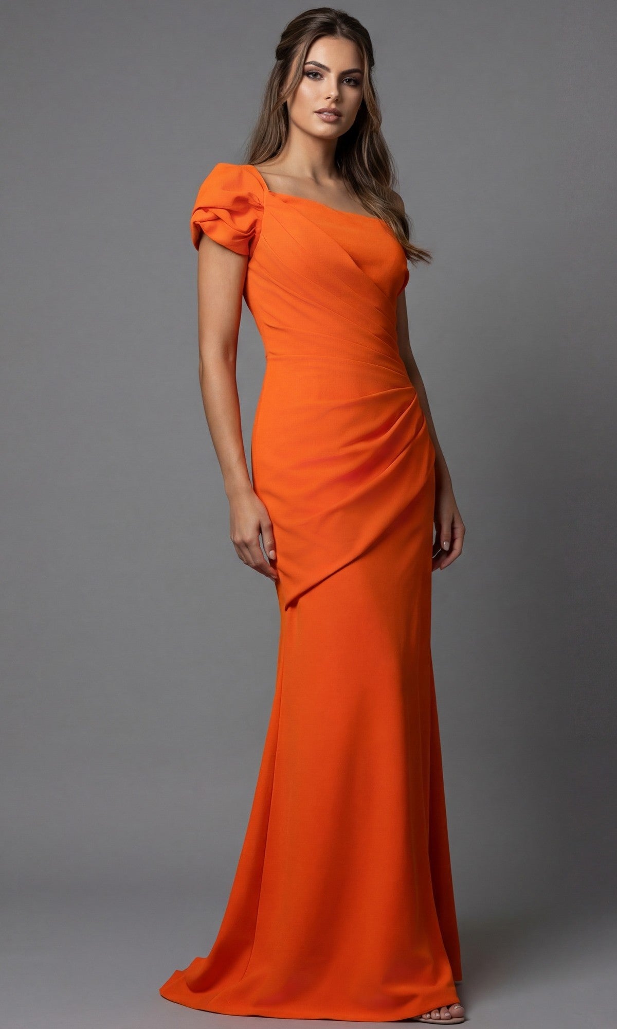 A woman wearing the Jovani 09961 long formal dress in orange, featuring puffed short sleeves, stands against a plain gray background.