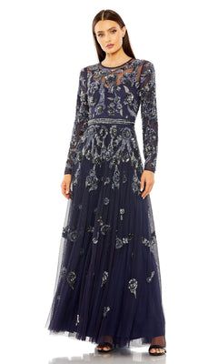 A woman stands against a white background wearing the Mac Duggal 10013 long sleeve blue formal dress featuring silver floral embroidery and a sheer neckline.