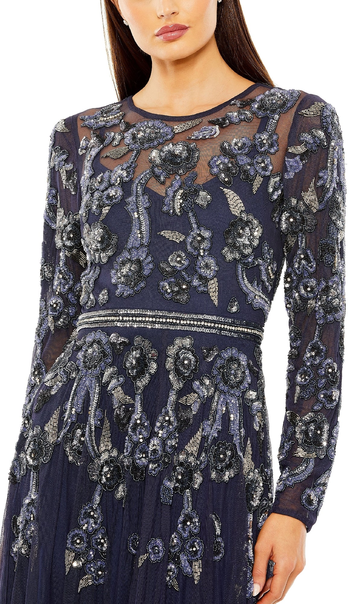 A woman wears the Mac Duggal 10013 long sleeve long blue formal dress, featuring sheer sleeves and intricate silver floral beadwork on the bodice, waist, and sleeves.