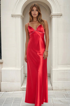 Woman wearing a red satin dress standing in front of a white architectural background