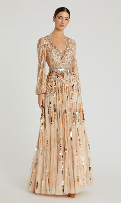 A woman wears the Long Beaded Bisque Formal Dress, Mac Duggal 10059—a beige gown with a V-neckline, long sleeves, and allover metallic sequin embellishments.