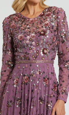 A woman wears the Mac Duggal 10063 Long Sleeve Beaded Formal Dress in mauve, featuring intricate multicolored floral embroidery and beadwork—a stunning formal gown.
