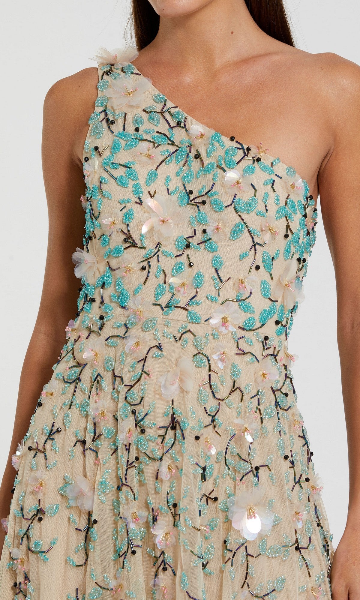 A woman in the Mac Duggal 10086 Midi Wedding Guest Dress, featuring a beige one-shoulder design with turquoise and white floral embroidery and sequin embellishments.
