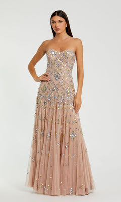 A woman poses gracefully against a white background in the Mac Duggal 10100, a strapless light pink prom gown adorned with silver and gold sequins.
