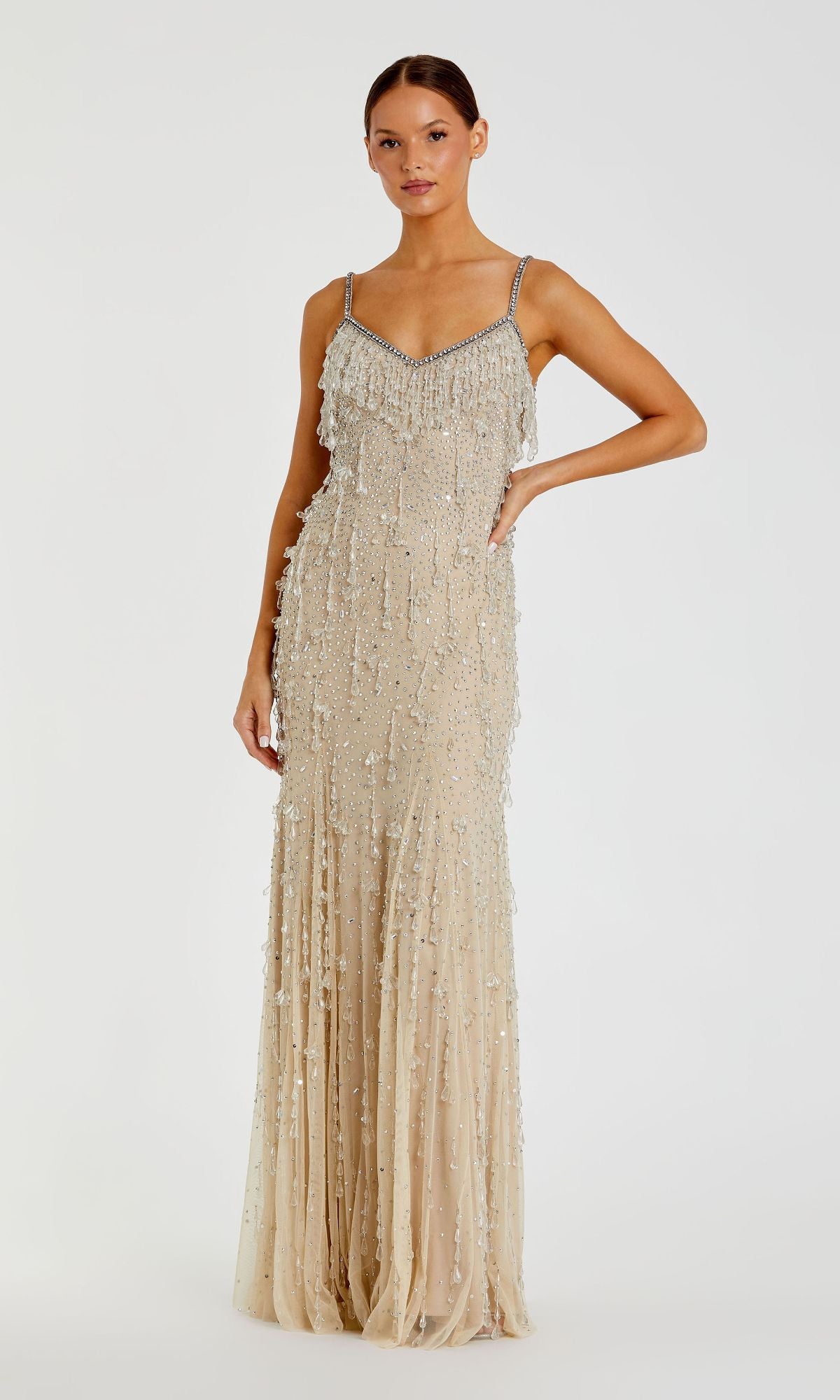 A woman poses against a plain light background in the Mac Duggal 10101 Fringed Long Nude Formal Dress—a floor-length, sleeveless gown featuring beaded fringe for an elegant, contemporary look.