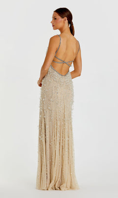 A woman in the Mac Duggal 10101 Fringed Long Nude Formal Dress with thin straps and an open back stands facing slightly away against a plain white background.