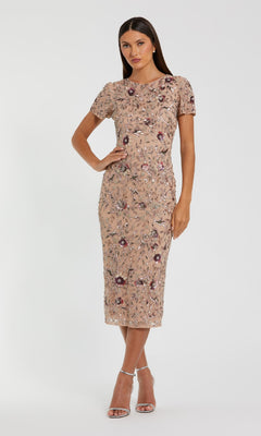 A woman models the Mac Duggal 10102 Beaded Midi Wedding Guest Dress, featuring a fitted beige silhouette with floral embroidery, posing against a plain background with one hand on her hip.