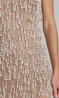 A close-up of the Short Cocktail Dress: Mac Duggal 10121, a sleeveless mini cocktail dress adorned with cascading strings of small white beads and pearl fringe, shown worn with a bare arm visible.