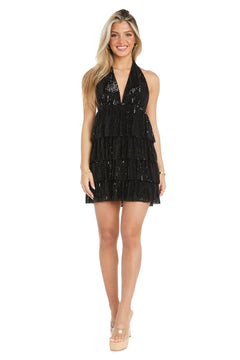 A woman stands facing forward, wearing the Black Sequin Halter Party Dress: Morgan 10142, featuring a sleeveless design, deep V-neck, tiered ruffle skirt, and paired with nude platform heels.