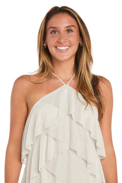 A woman with long brown hair is wearing the Short Homecoming Dress: Morgan 10196, a white halter dress with ruffled tiers, as she stands and smiles at the camera against a white background.