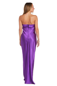 A woman is shown from the back wearing the Morgan 10219, a long, strapless, purple satin prom dress with a sheath silhouette, photographed against a white background.