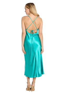 A woman faces away in the Morgan 10248 Satin Semi-Formal Midi Dress with thin crisscross straps, cowl neckline, open back, and teal sheen, styled with beige heeled sandals—ideal for semi-formal events.