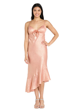 A woman wearing the Shimmer Midi Semi-Formal Dress: Morgan 10251, a peach-toned party dress with chest flower detail and asymmetrical ruffled hem, paired with silver heels.